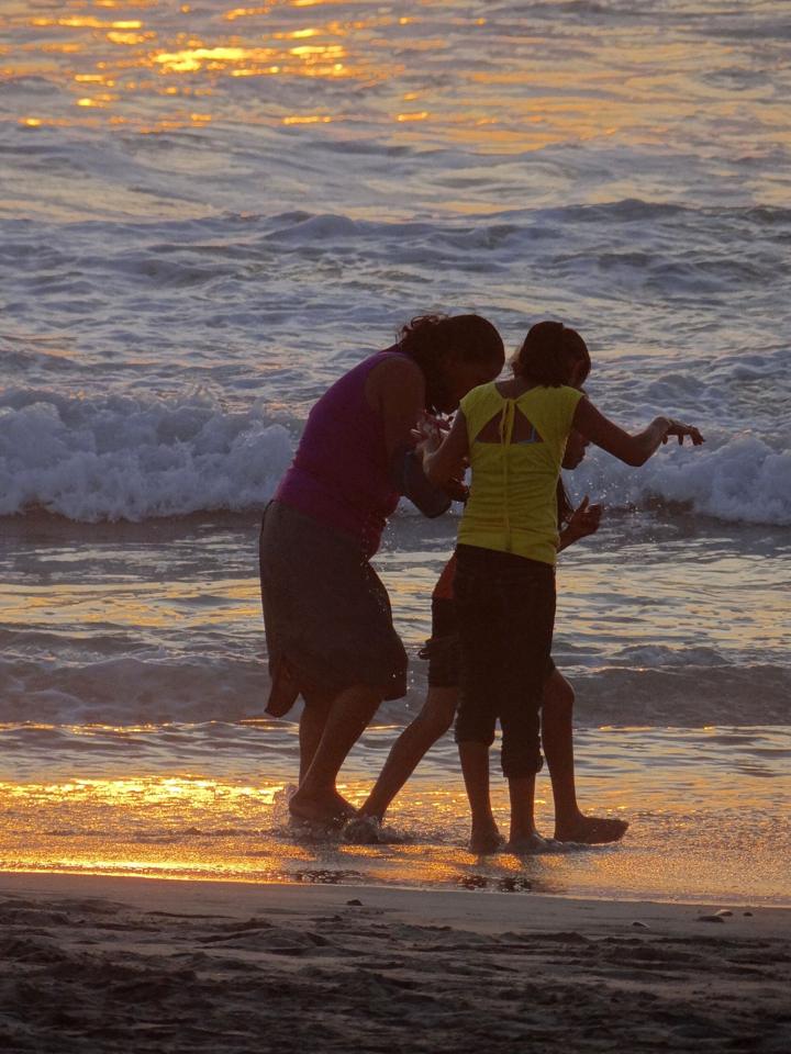 Two kids playing in the shore break at sunset on Zicatela Beach