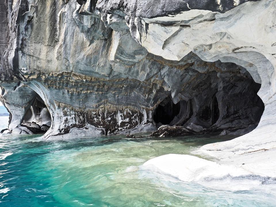 Swirling blue and white marble cave walls over turquoise water